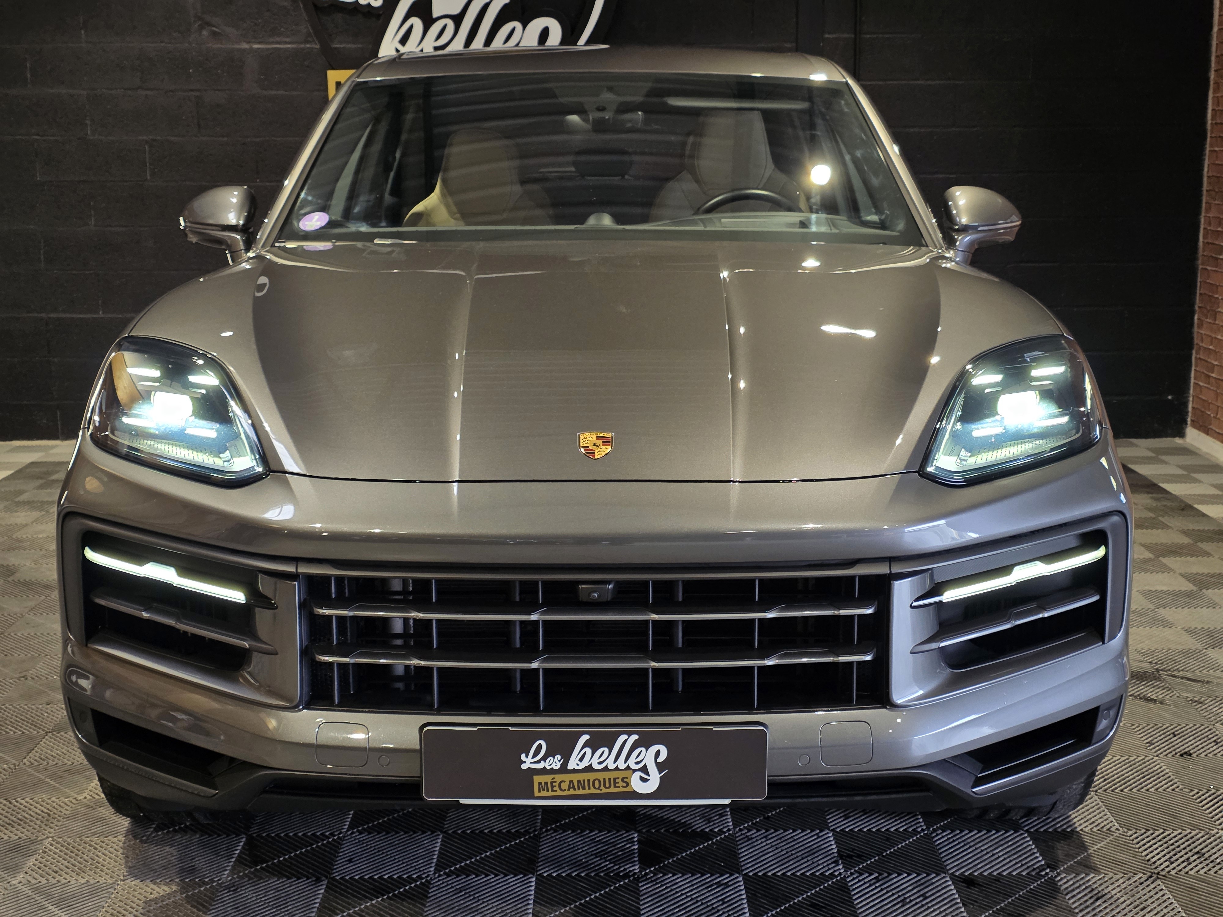 Face avant du Porsche Cayenne gris Quarzit avec phares LED Matrix allumés et badge Porsche couleur, Les Belles Mécaniques