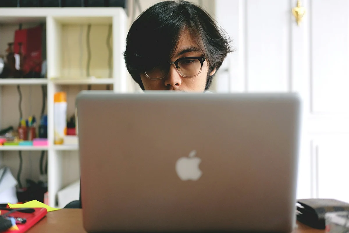 A learner with glasses looking at a laptop screen.
