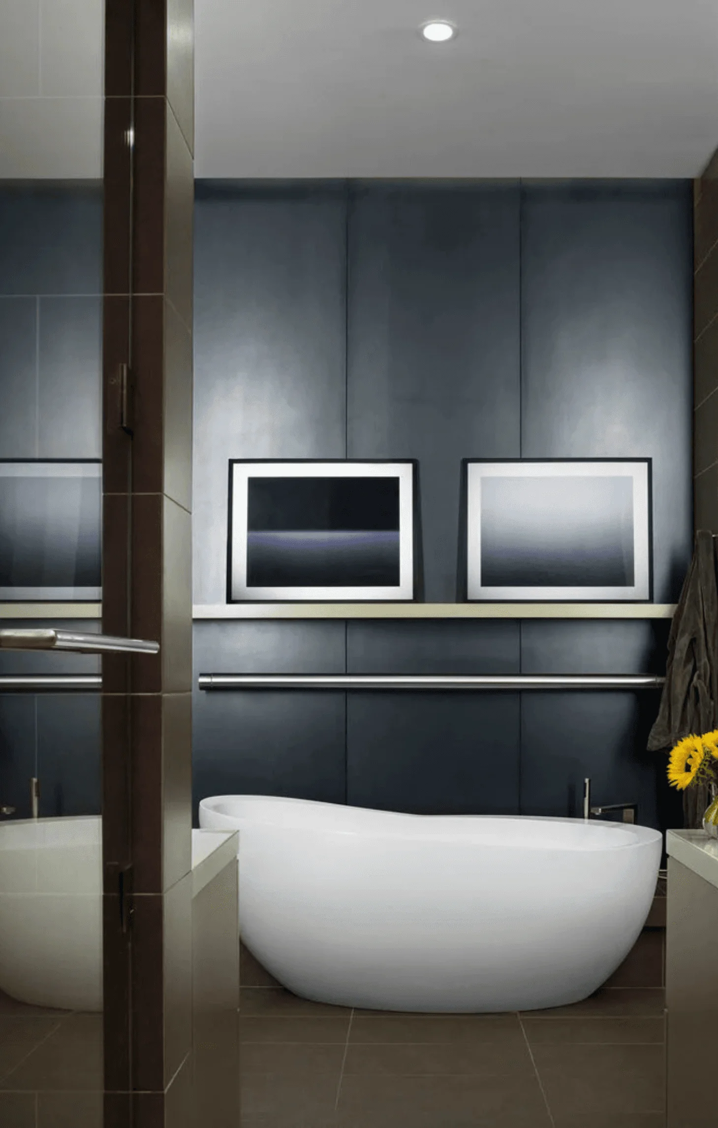 The primary bathroom features a freestanding soaking tub beneath framed photography and a slate-paneled wall