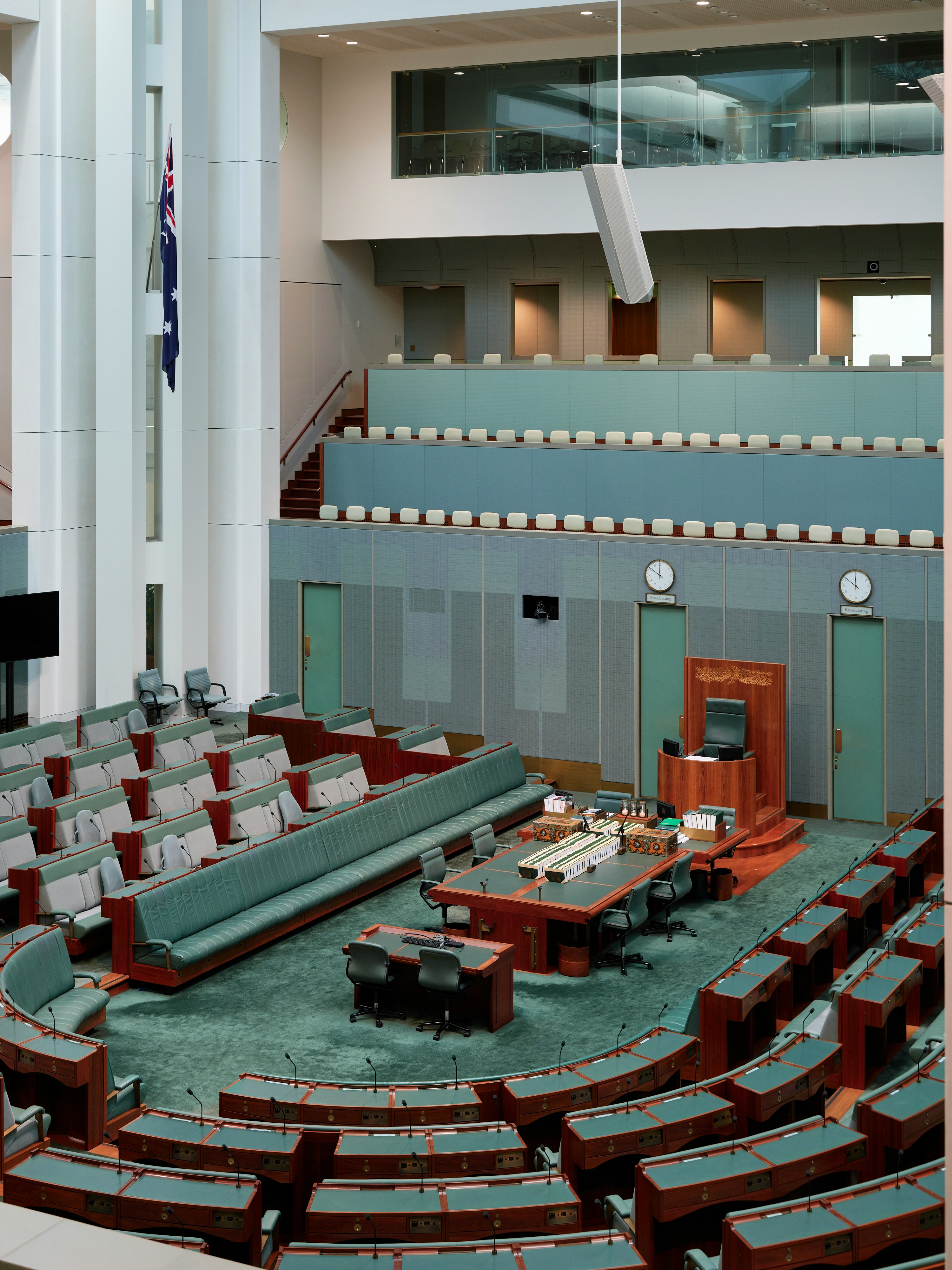 Interior of a parliamentary chamber featuring seating arrangements and a central podium, with natural light filtering in.