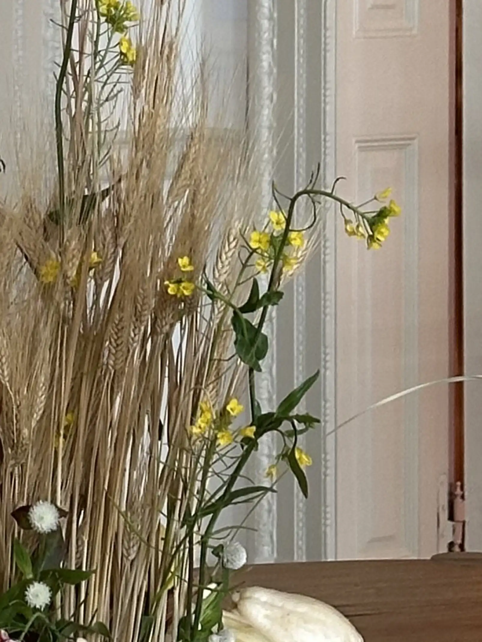 Detalle de espigas de trigo y flores amarillas en composición natural para decoración botánica interior.