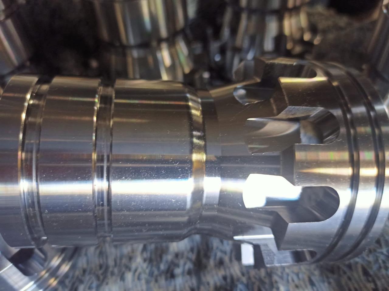 Close-up detail of a complex precision-machined mechanical component featuring intricate grooves and polished surfaces.