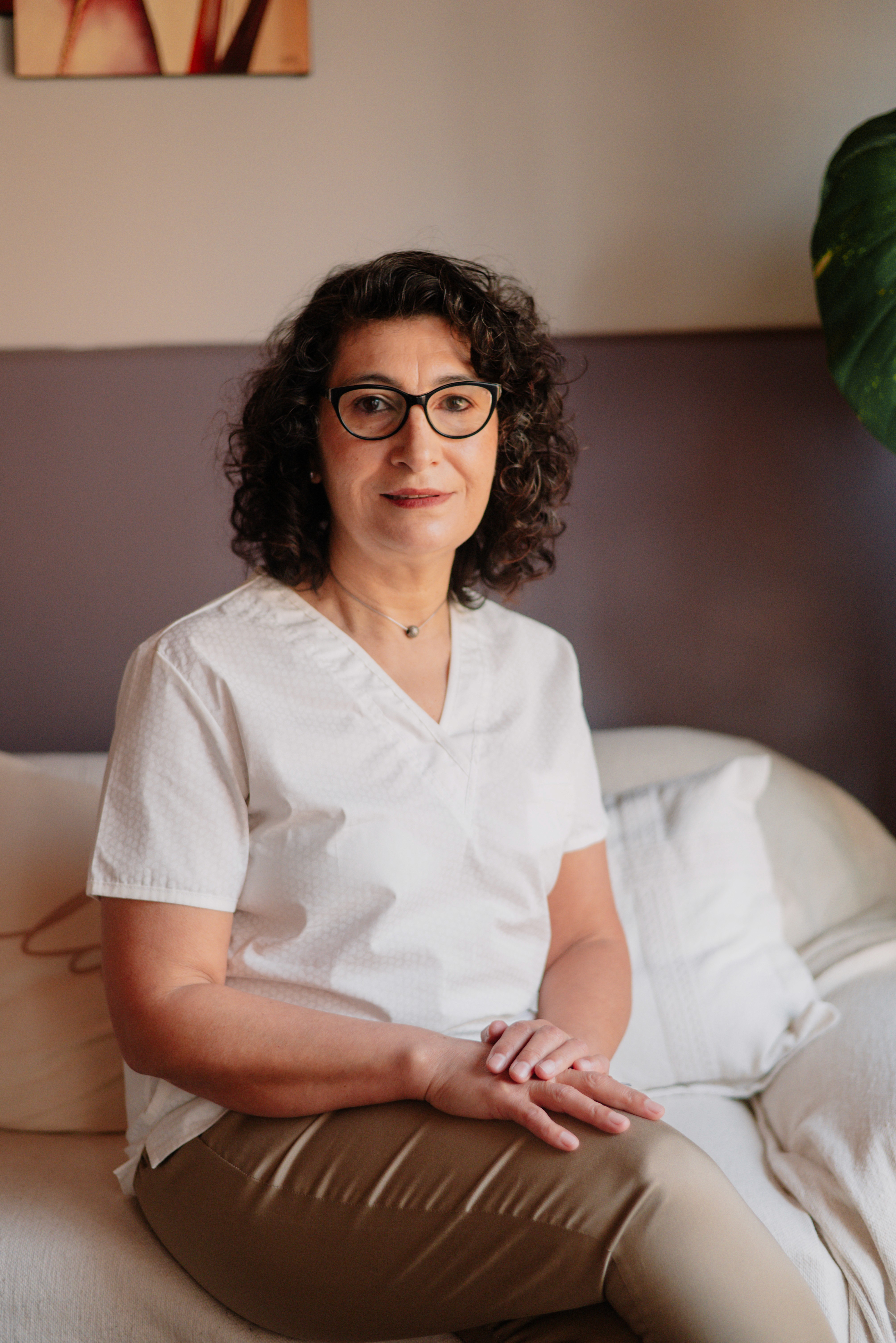 A person stands outdoors in a natural setting with lush green trees under a clear sky, wearing a dark sweatshirt, and looking into the distance.