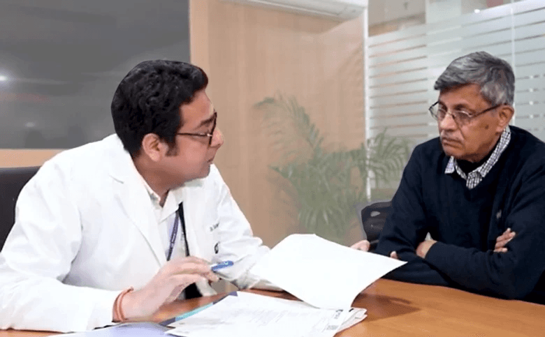 Dr. Tushar explaining medical reports and treatment options to a patient in his office.