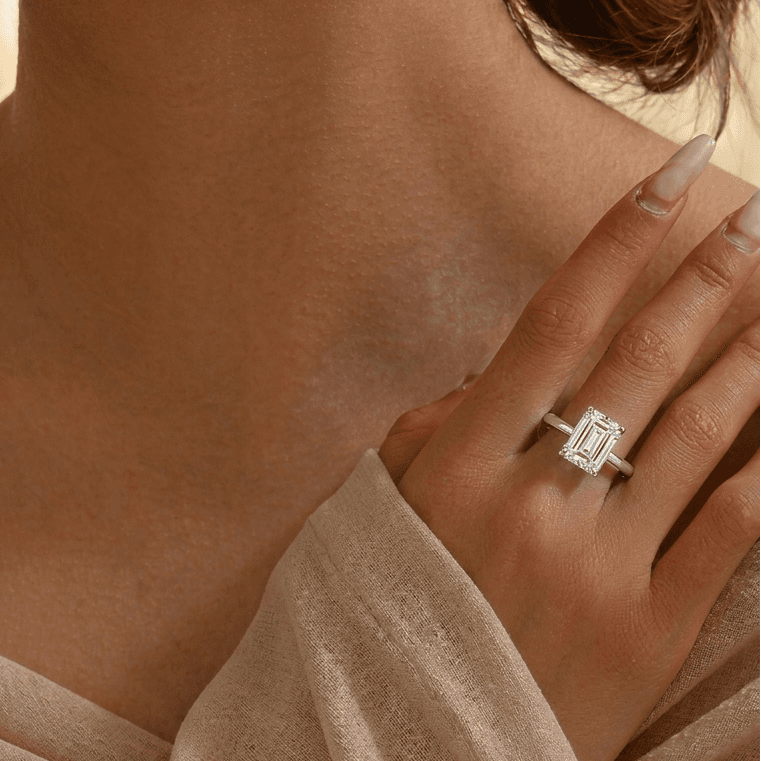 Close-up of a woman wearing a diamond ring on a soft beige background