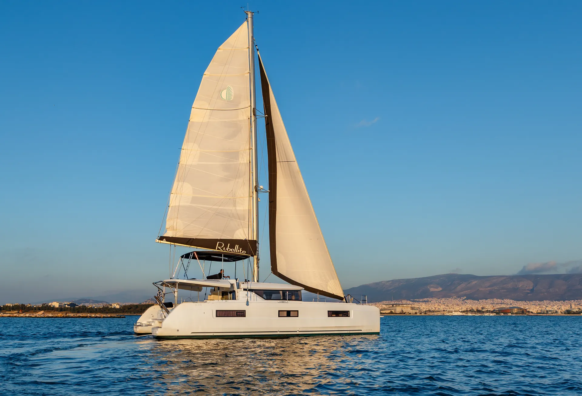 White Rock 36 speedboat with captain at helm cruising calm blue waters near Paros coastline with hills in background.