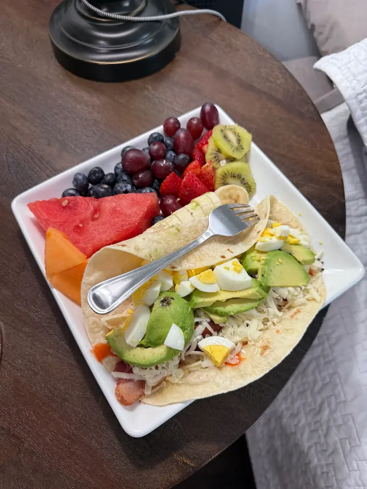 Breakfast wrap with egg, bacon, avocado, and cheese on a tortilla.