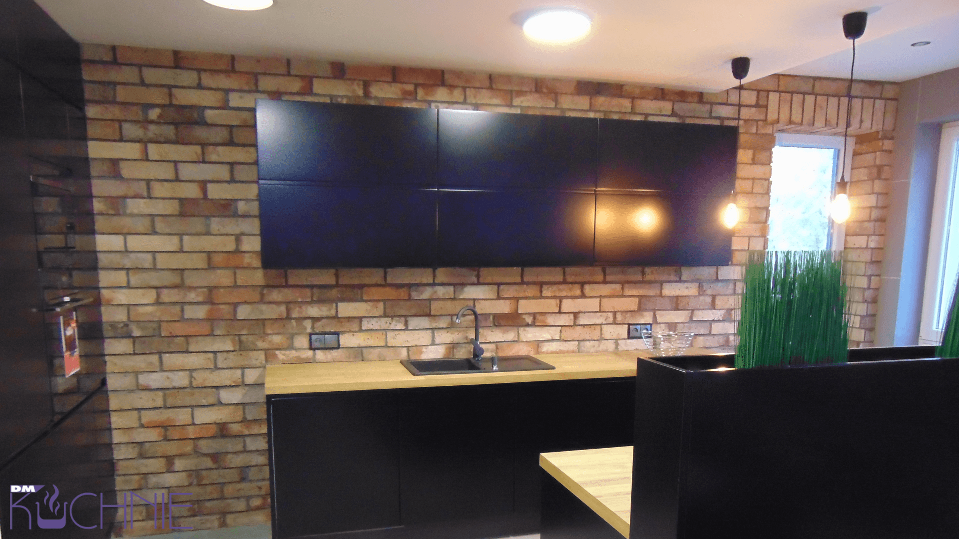 Kuchnia na wymiar Warszawa – industrialna zabudowa z cegłą, czarne szafki i nowoczesne oświetlenie