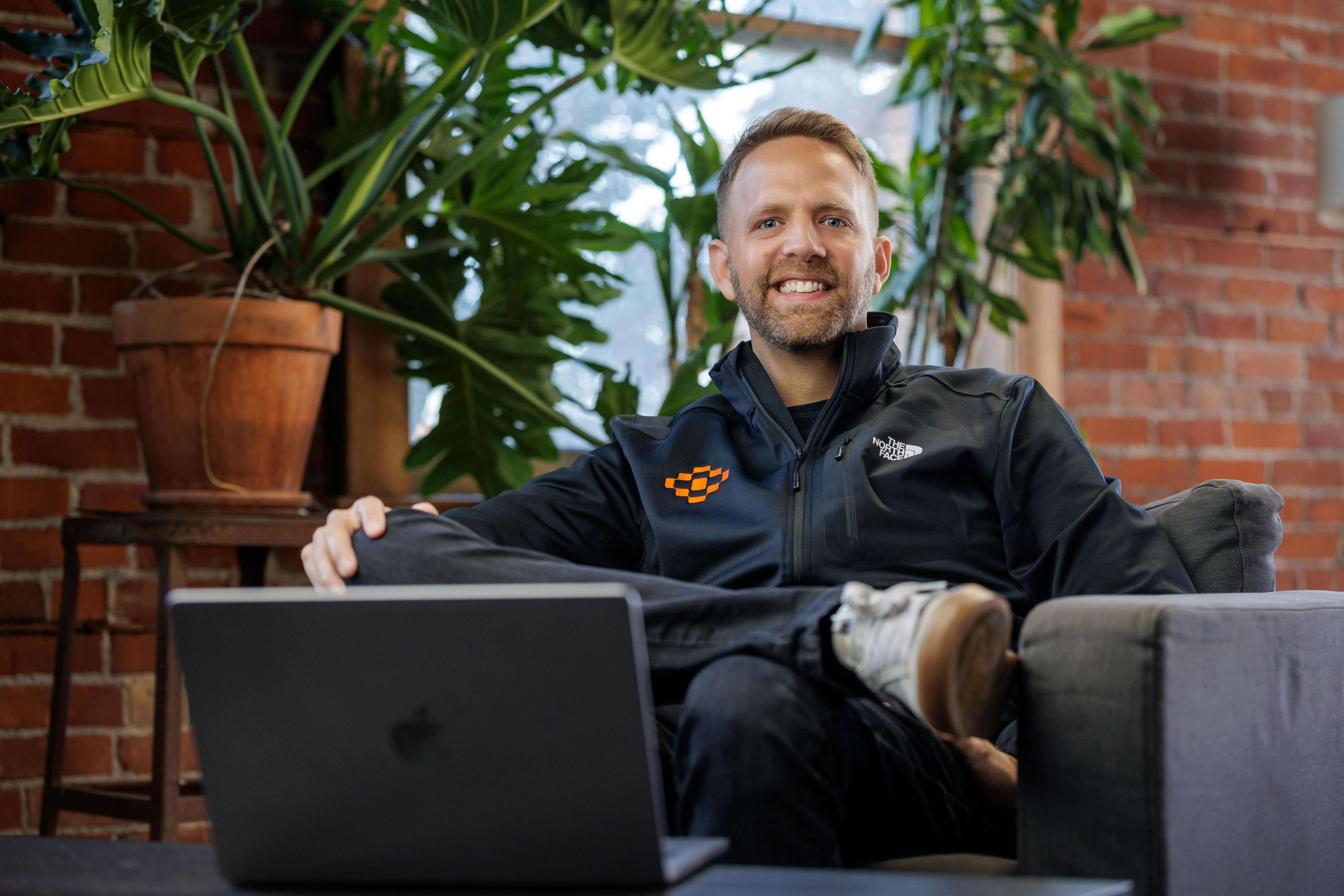 A large group photo of diverse team members gathered in an industrial-style space with arched ceiling.