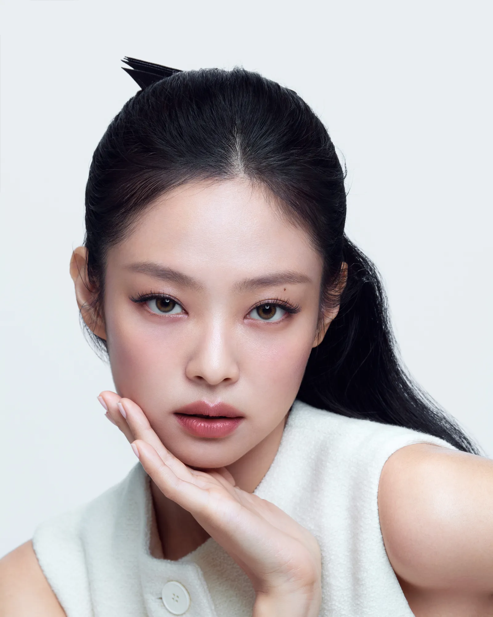 Jennie of BLACKPINK posing with her hand under her chin, wearing soft pink makeup, for Hera Beauty