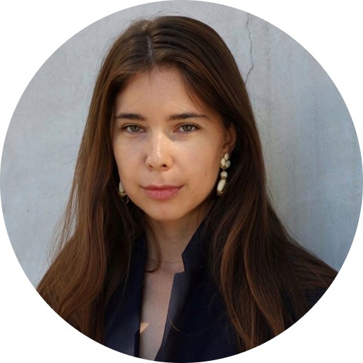 Editorial portrait of a young man with wavy hair in a knit sweater, looking over his shoulder in soft light.