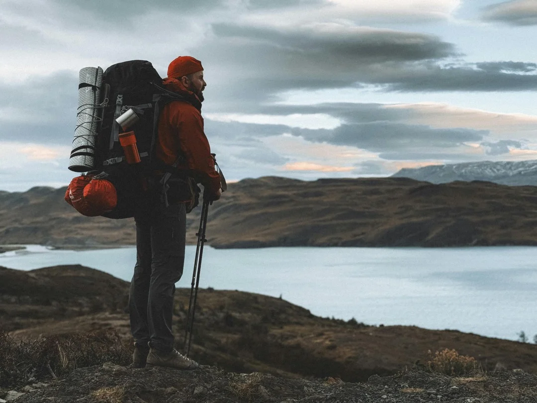 a male hiker taking in the view of a calm lake from high up