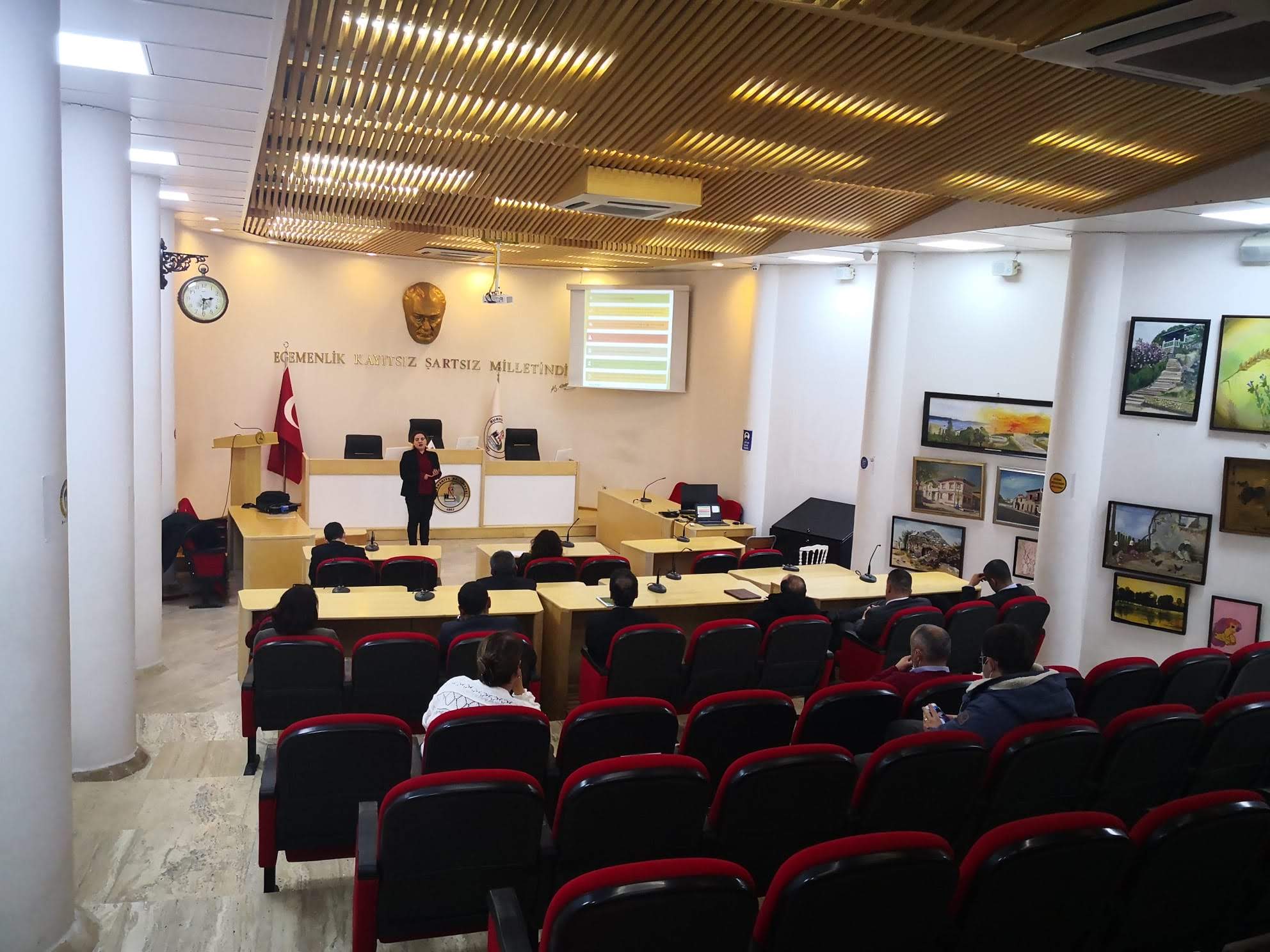 A smiling young man with crossed arms, wearing a plaid shirt and white t-shirt, poses against a dark background.