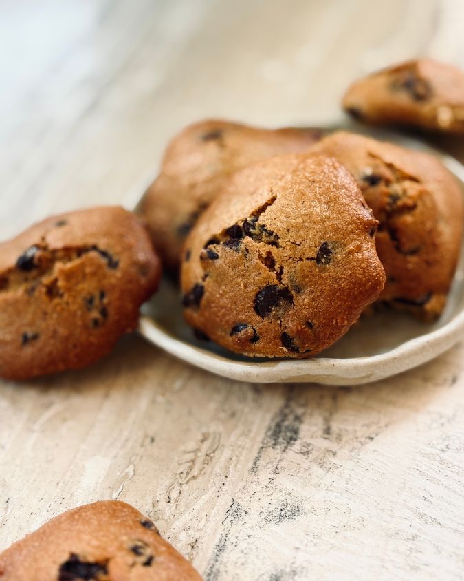Soft chickpea chocolate chip cookies on a small ceramic plate on a wooden surface.