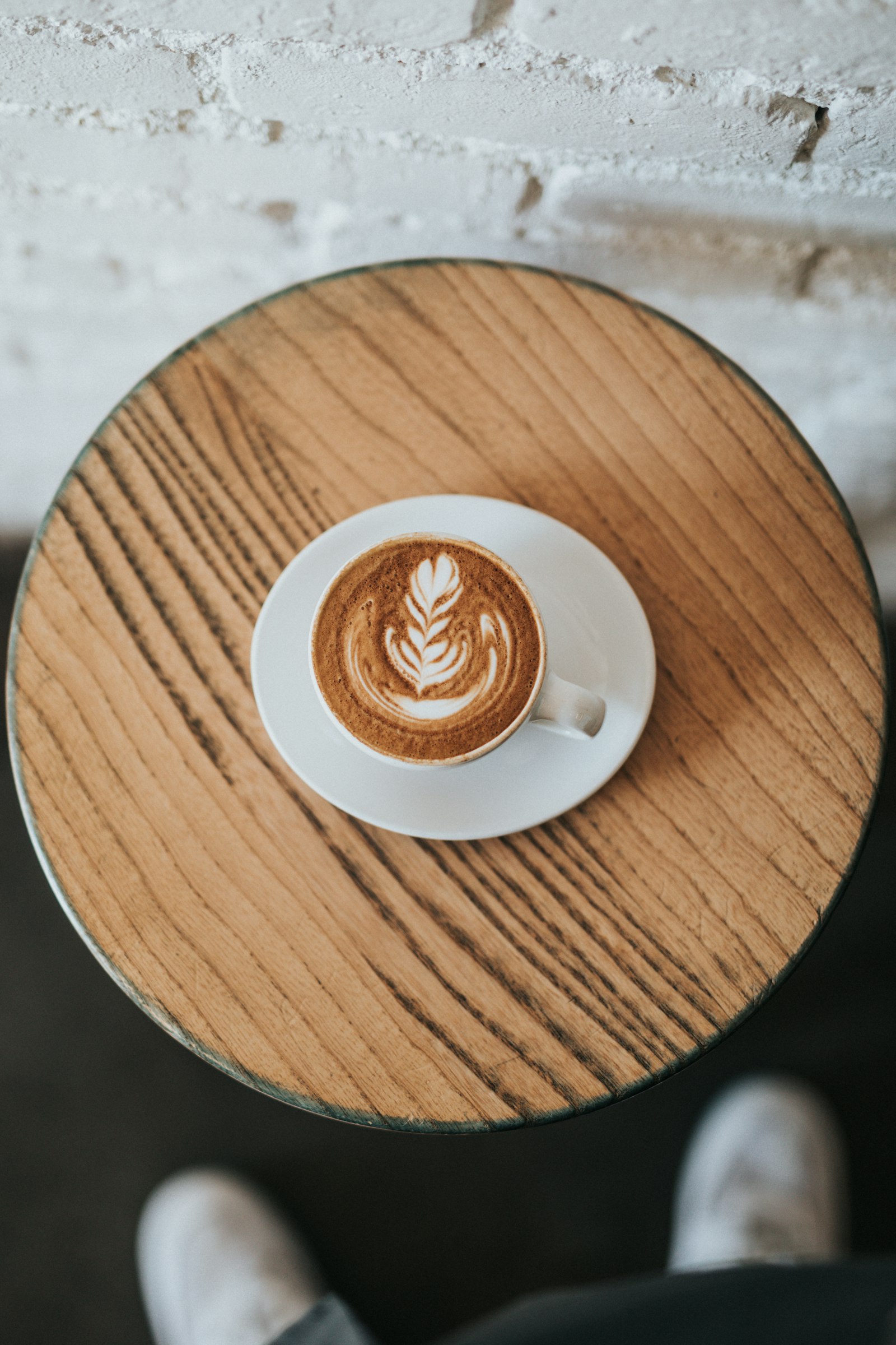 Persona con una taza de café latte sentada en una mesa de café