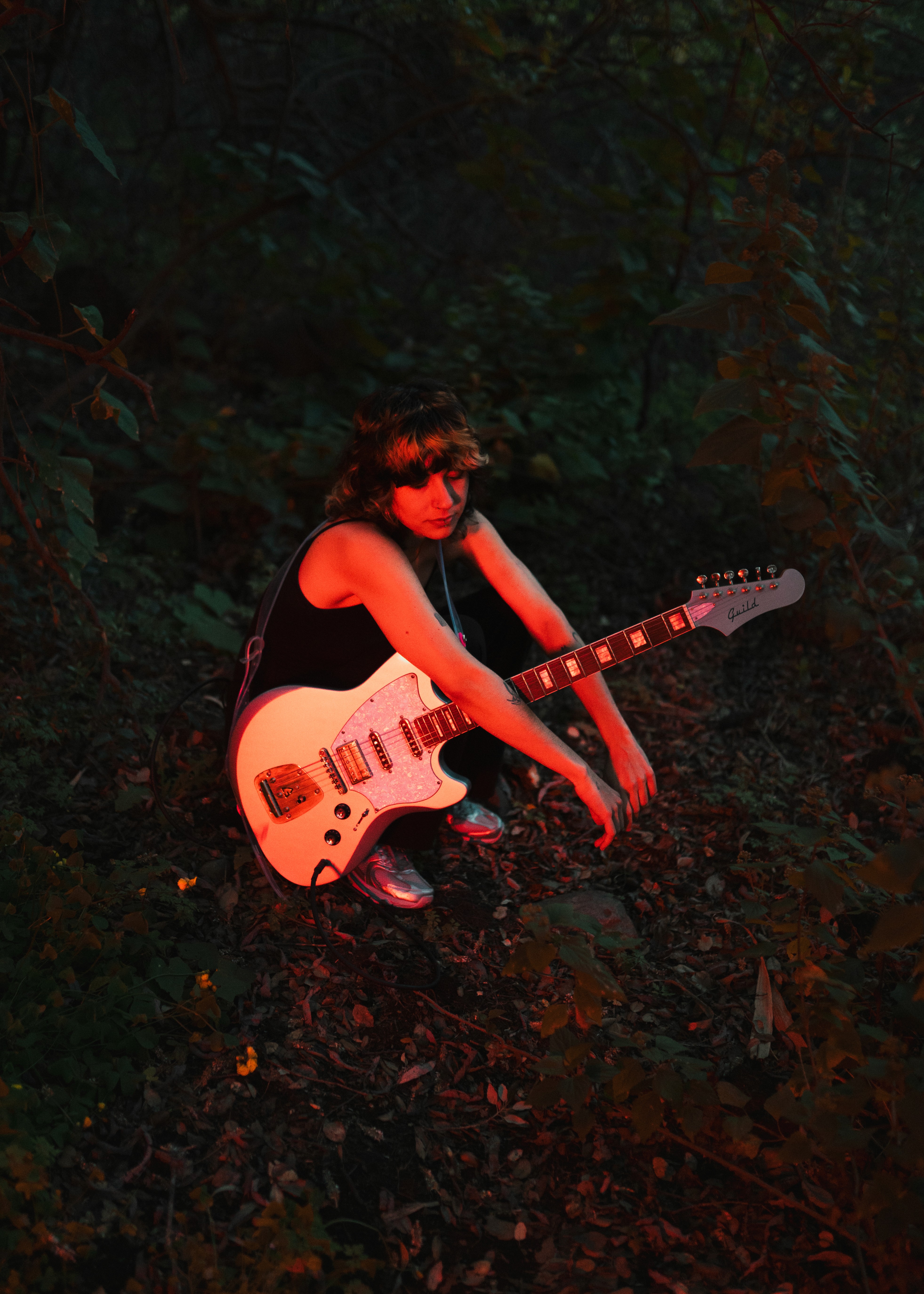 Artist Velvet Flores inside a pond staring at the camera. She is surrounded by beautiful Canary Islands flowers