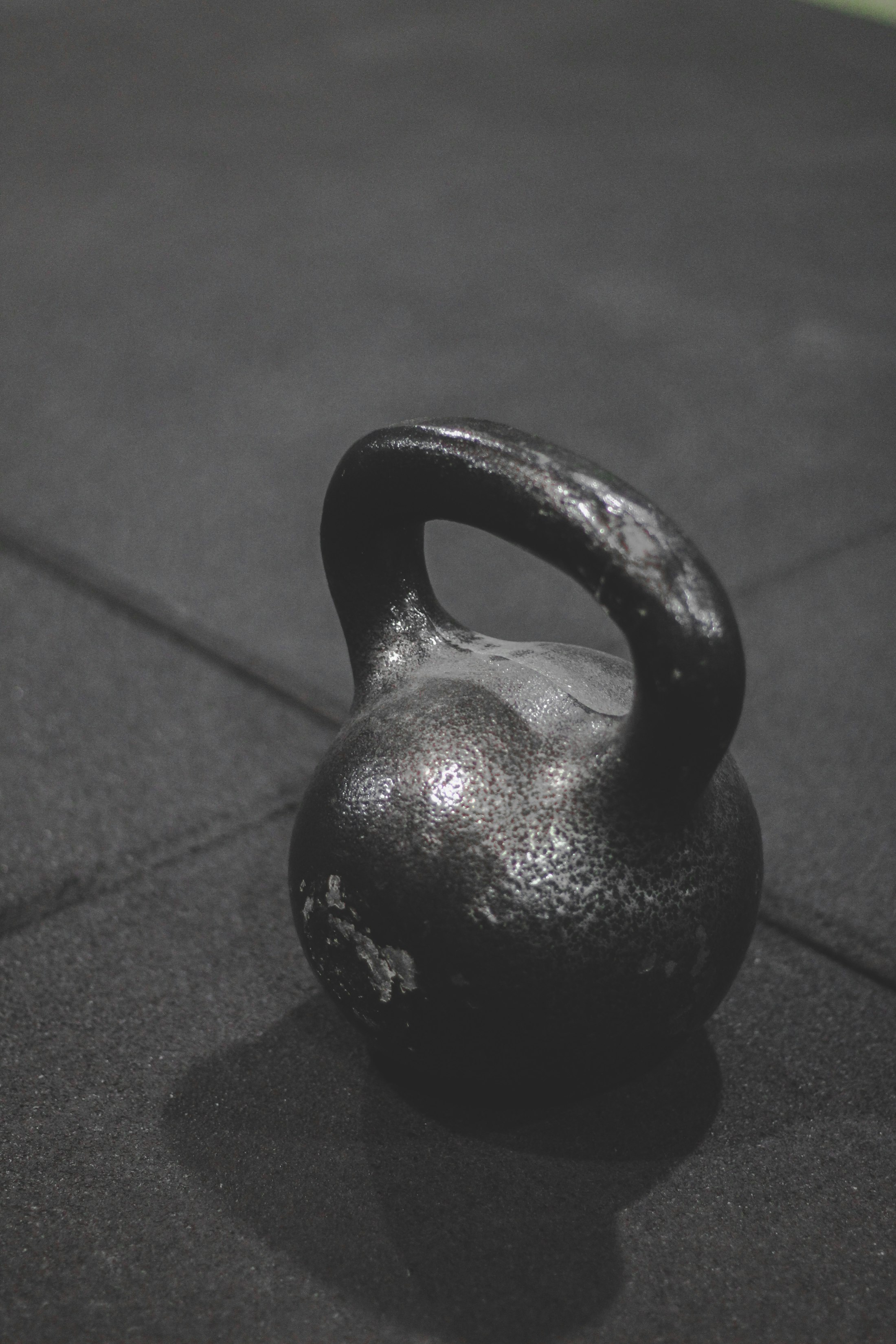 Einzelne Kettlebell auf dunklem Hallenboden