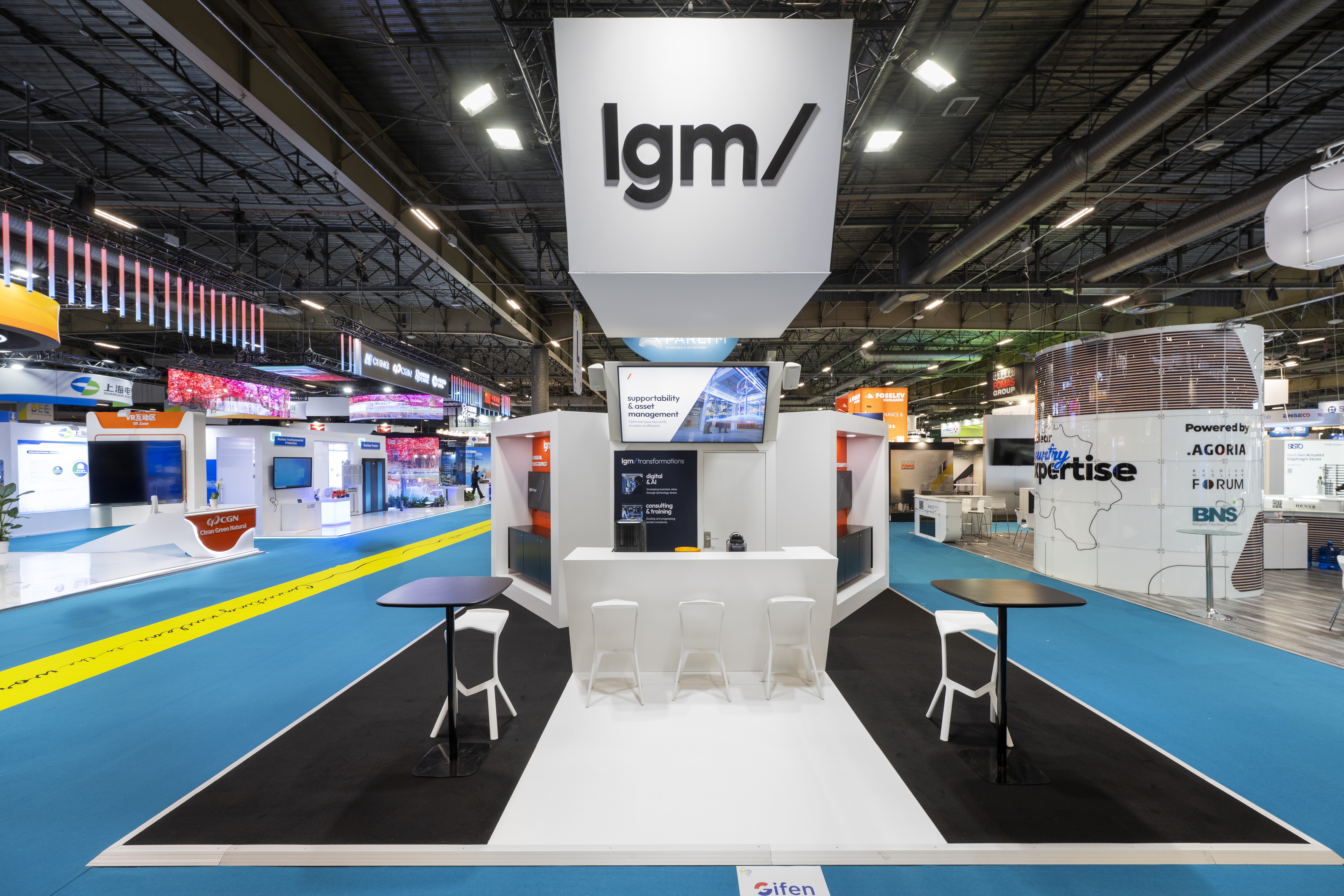 Stand LGM World Nuclear Exhibition WNE Paris 2025 réalisé par Expace – vue frontale avec caisson logo suspendu, façade turquoise et noire et espace d'exposition équipements nucléaires