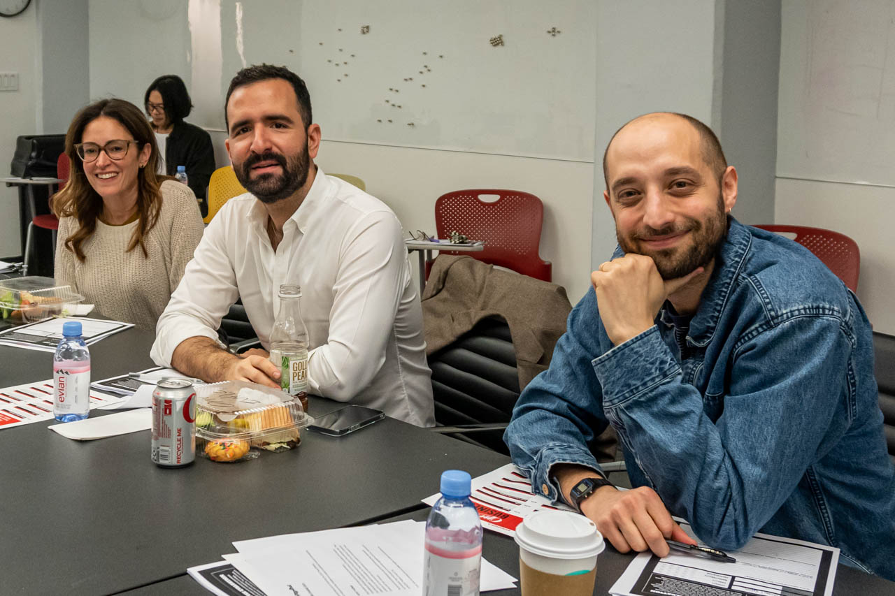 three people at a desk looking at the camera