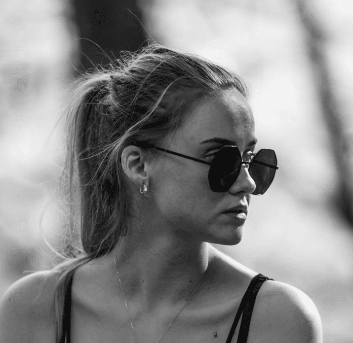 a young man wearing glasses standing in front of a mountain