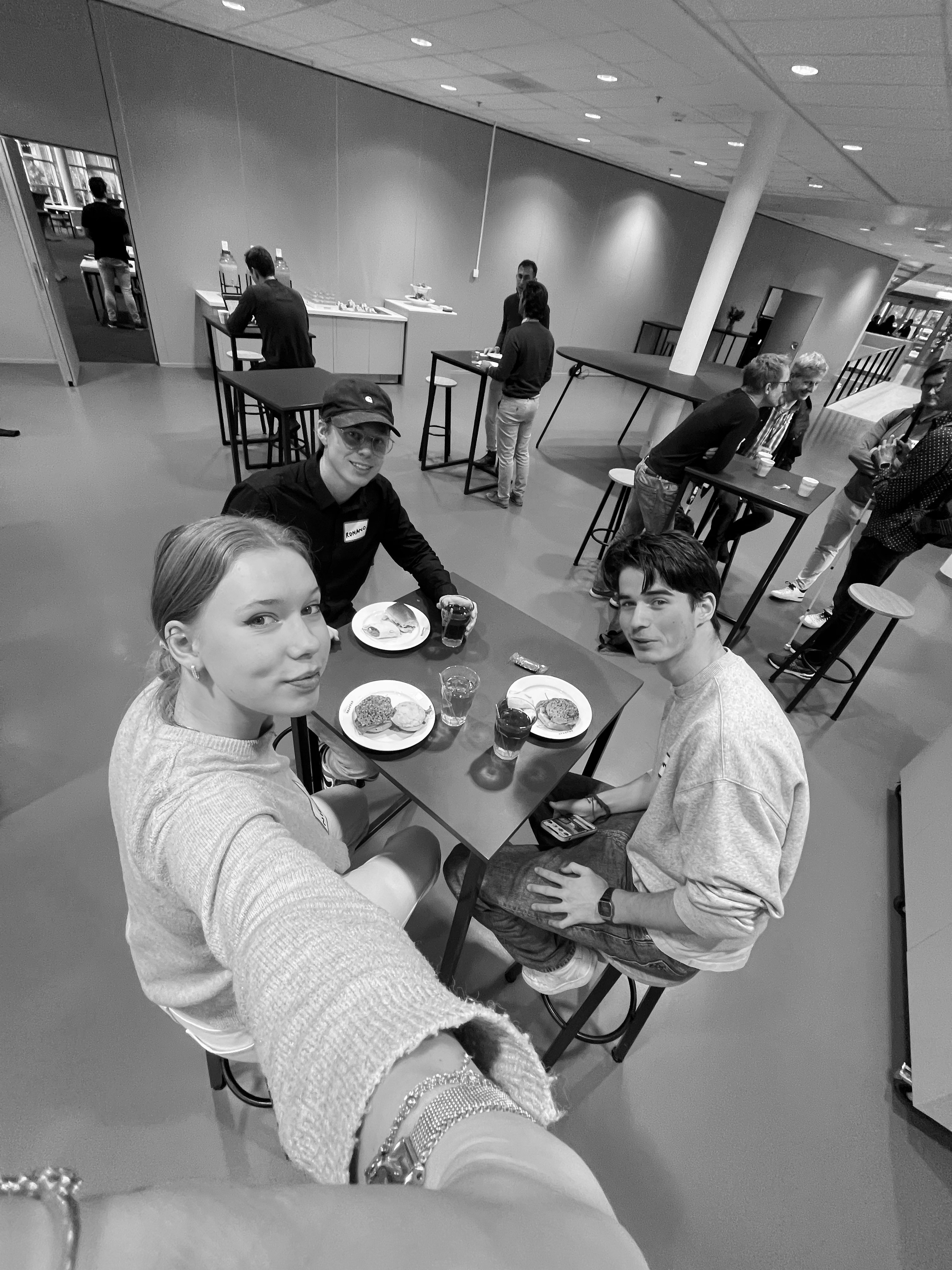 Seflie taken by a woman of three people sitting at a high table 