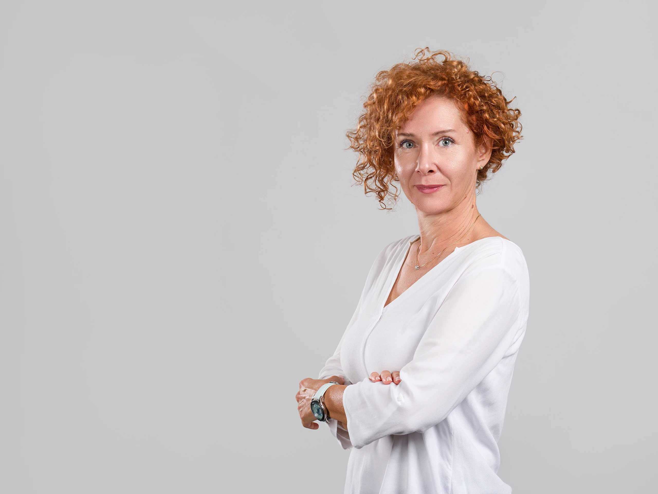 Corporate portrait of a confident woman standing naturally in a minimalist studio.