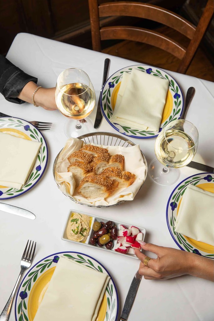 A top-down view of a dining table with plates of food, hands reaching for dishes, and a cozy atmosphere.