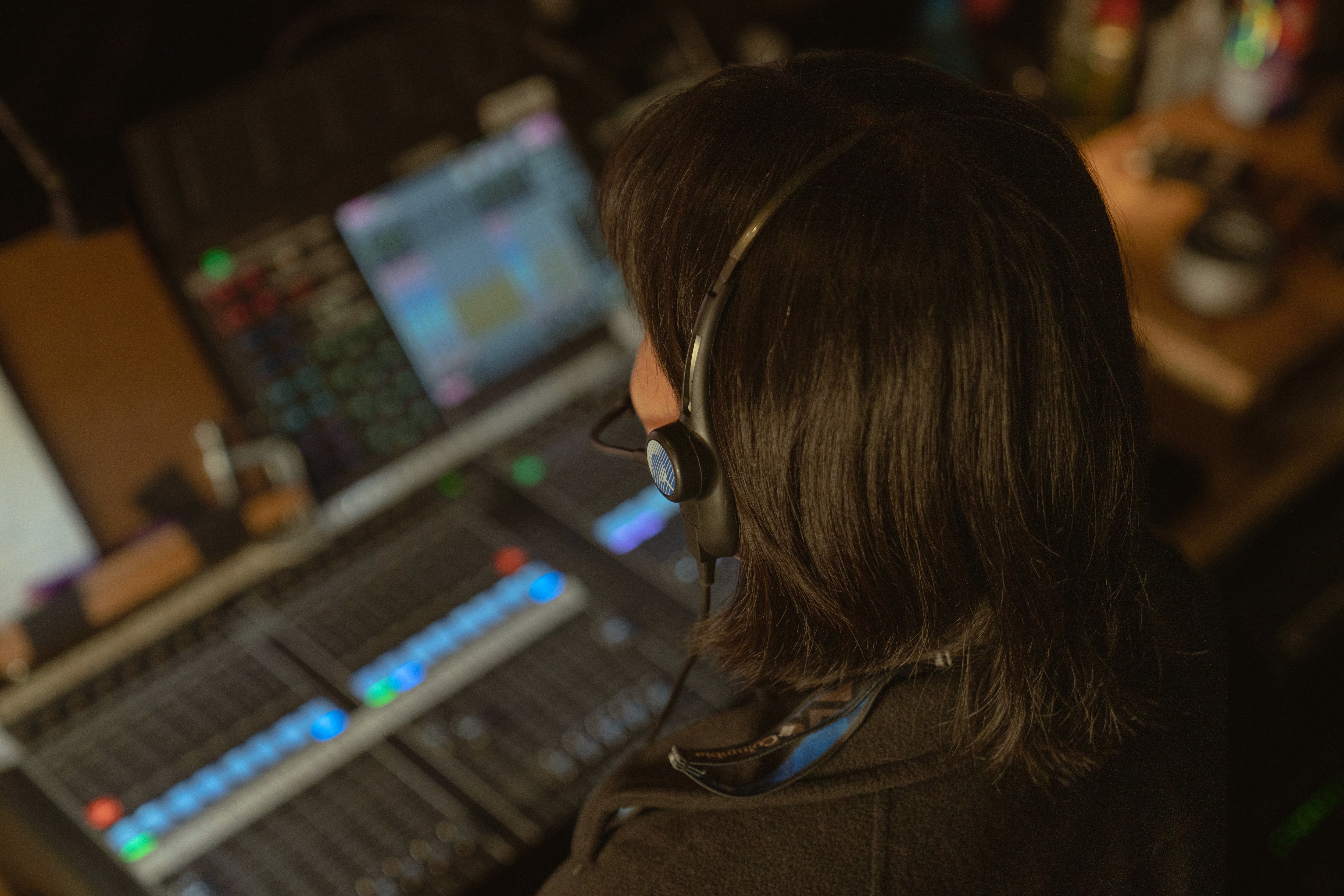 A person wearing a headset, seated at a professional control surface.