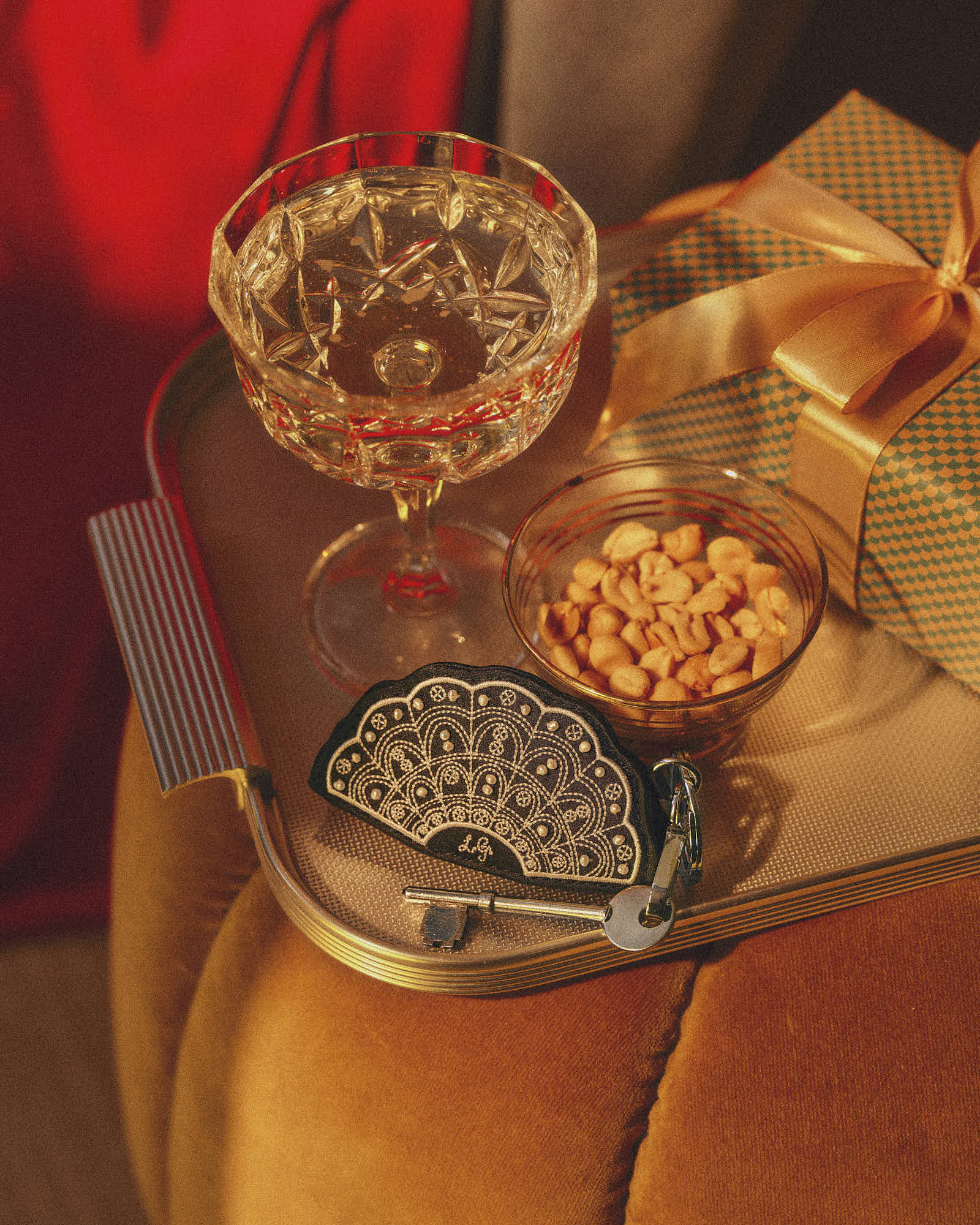 Elegant cocktail glass and peanuts on a tray with a gift box and vintage key.