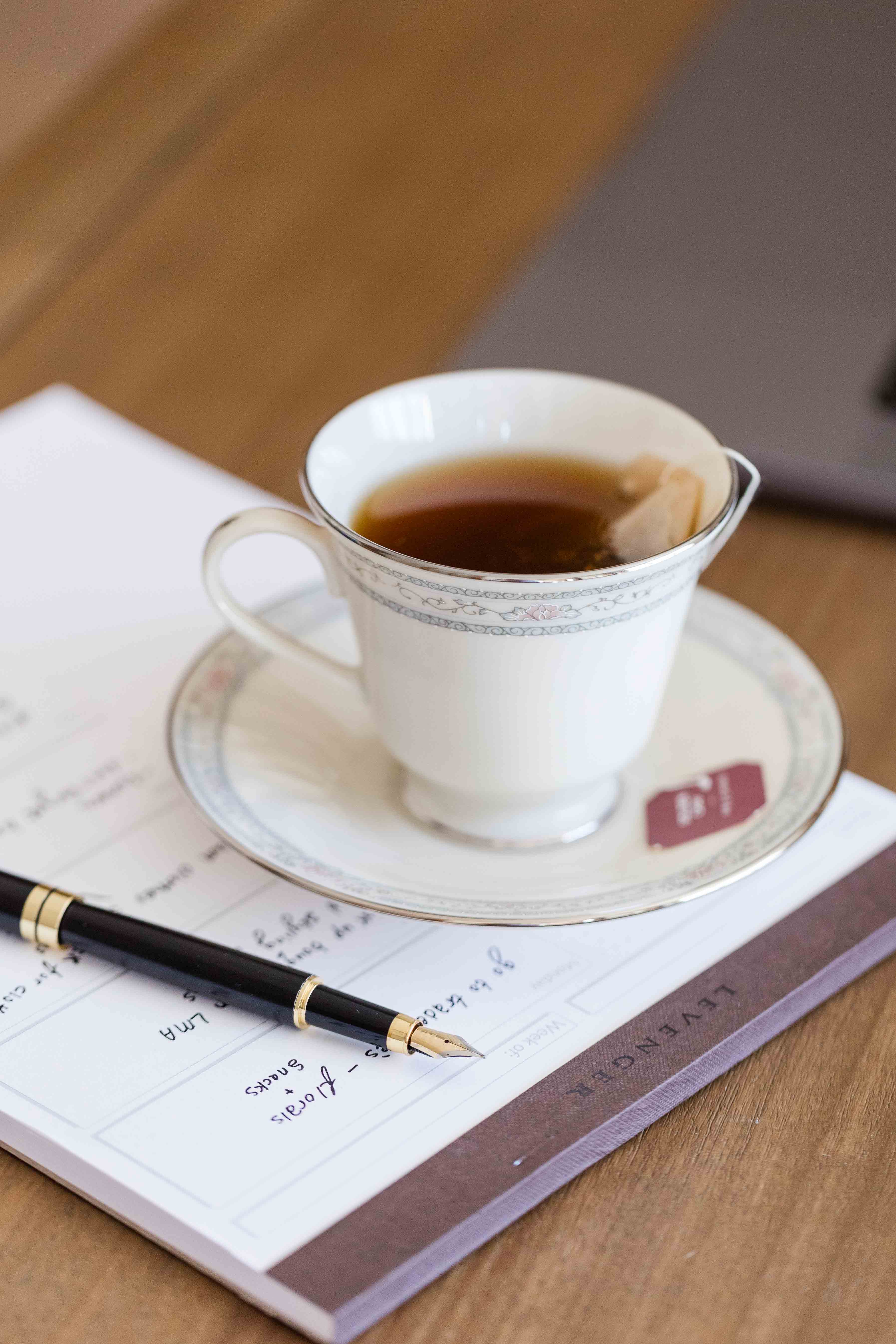 Picture of a cup of tea on a notepad and pen.