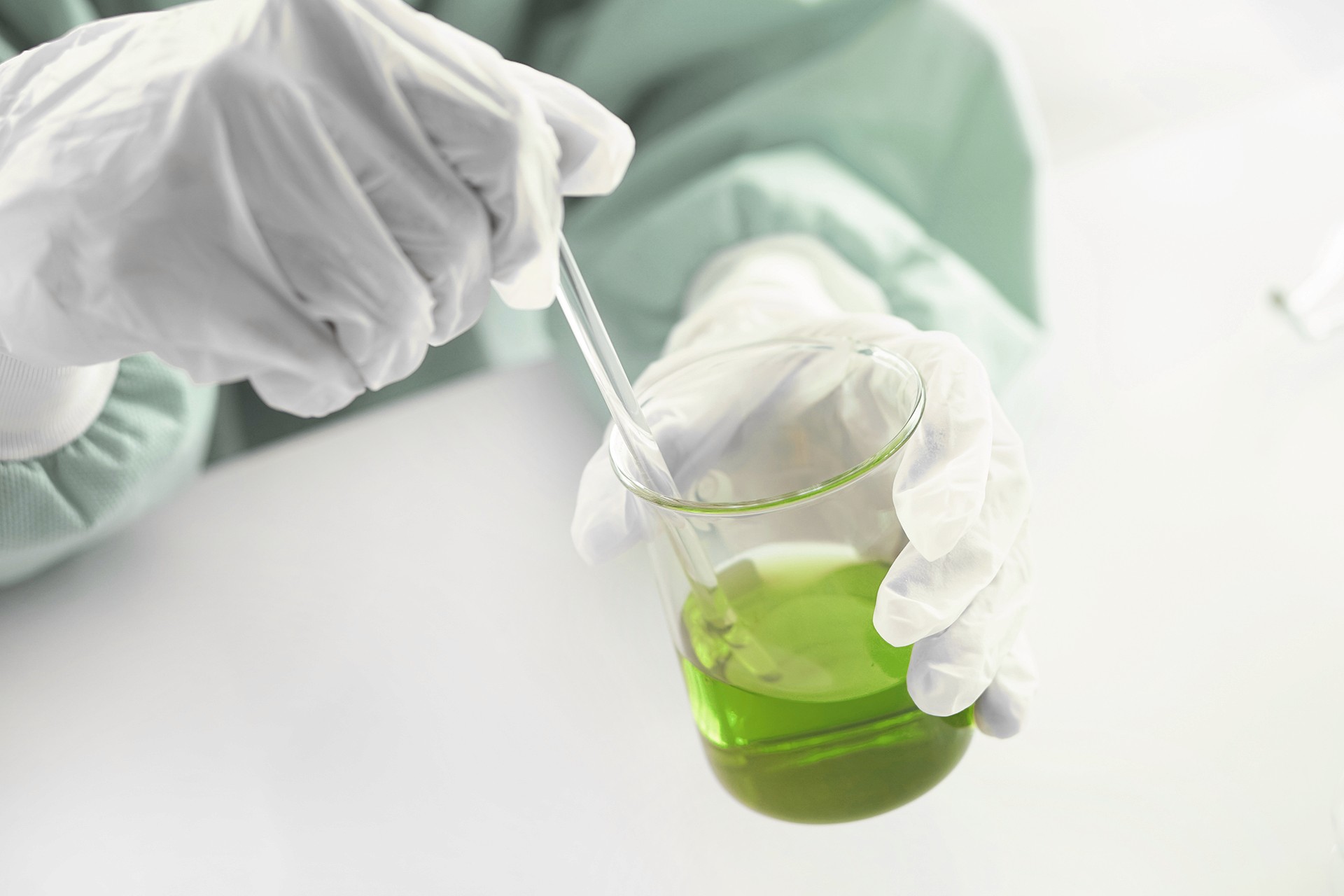 Researcher conducting experiment with green liquid in laboratory.