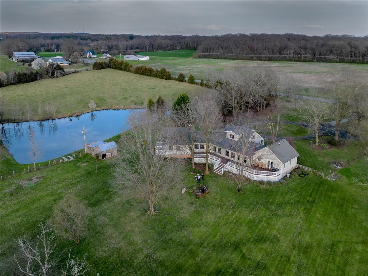 Drone aerial showing a vacation rental property, pond, acreage, and surrounding landscape