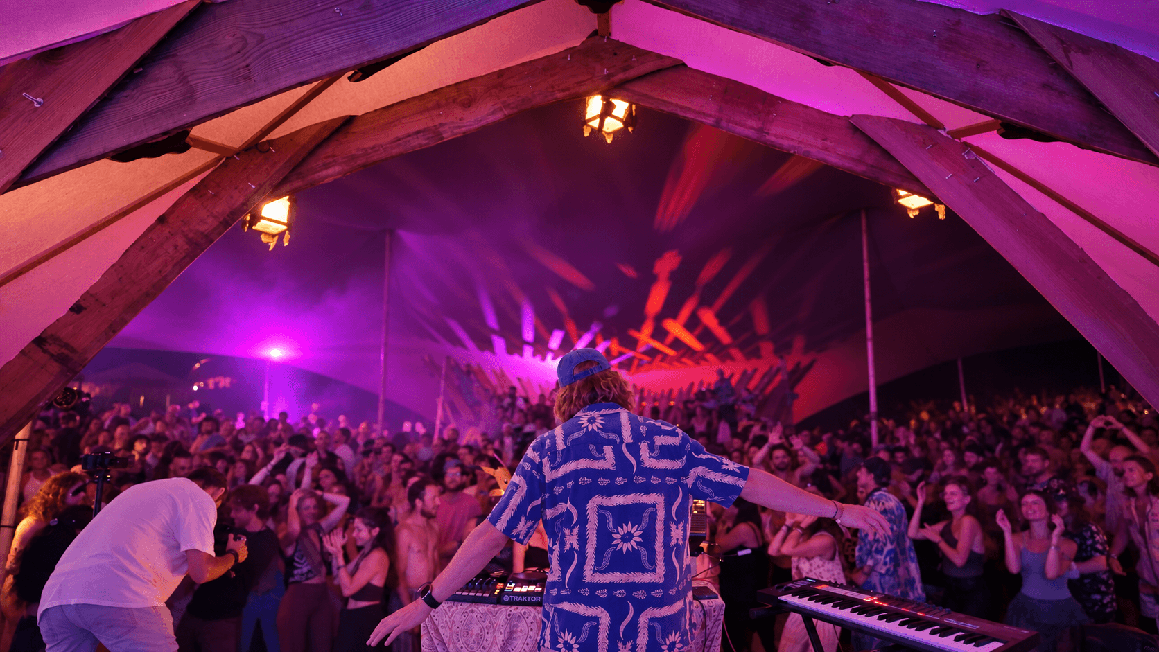 NIRVĀN behind the decks facing a crowd under purple stage lights