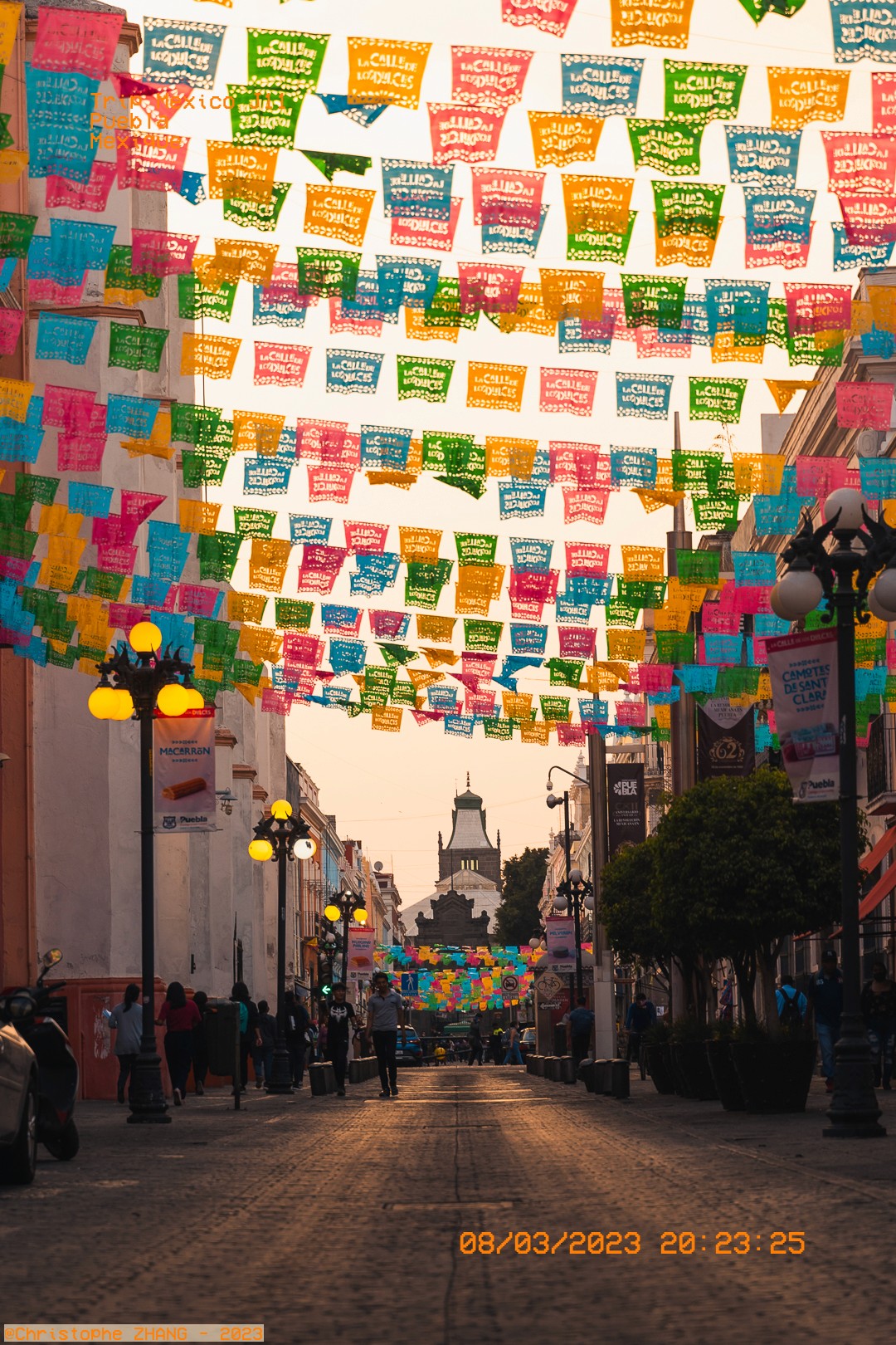 Rue colorée de Puebla décorée de banderoles festives sous une lumière dorée du soir.