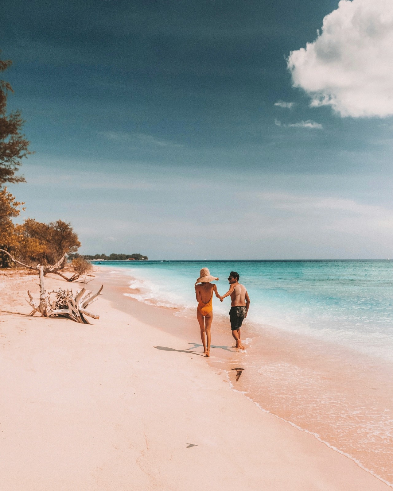 A mood picture two people in swimsuits holding hands walking along a white beach for Imprint’s client Westgate Resorts