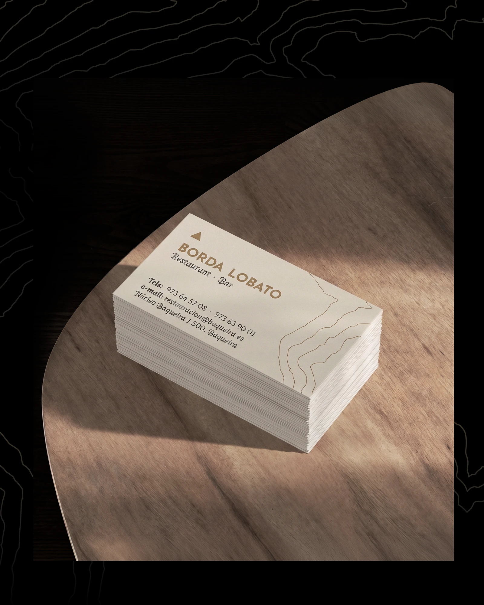 Stack of Borda Lobato business cards on a wooden table, brand identity design by Sebastian Saavedra