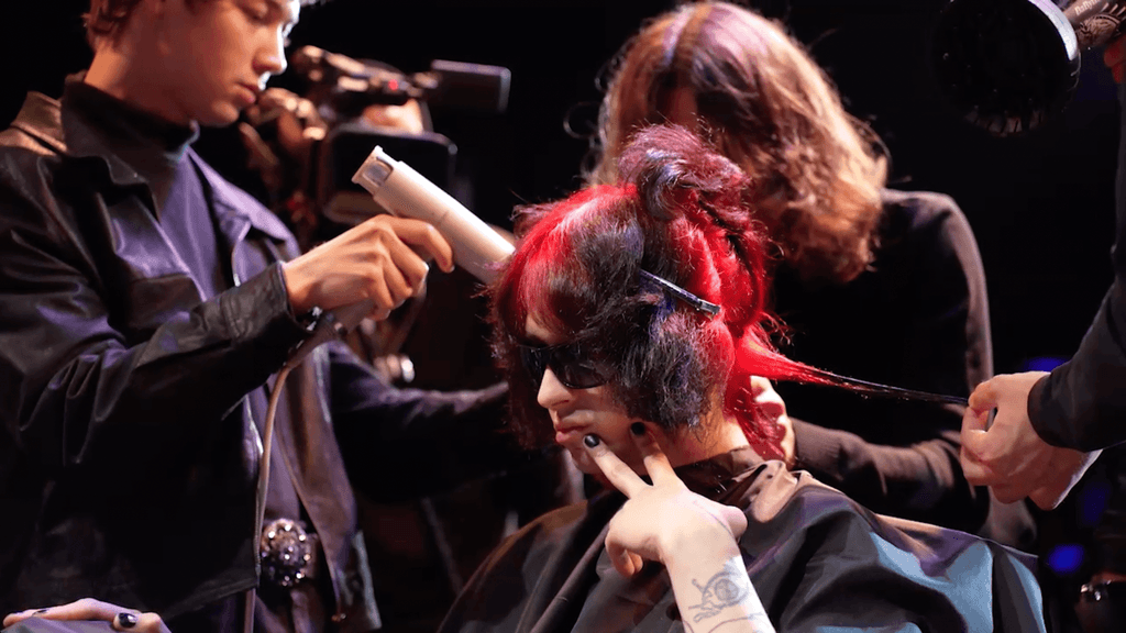 A girl with red hair is sitting in a barber shop