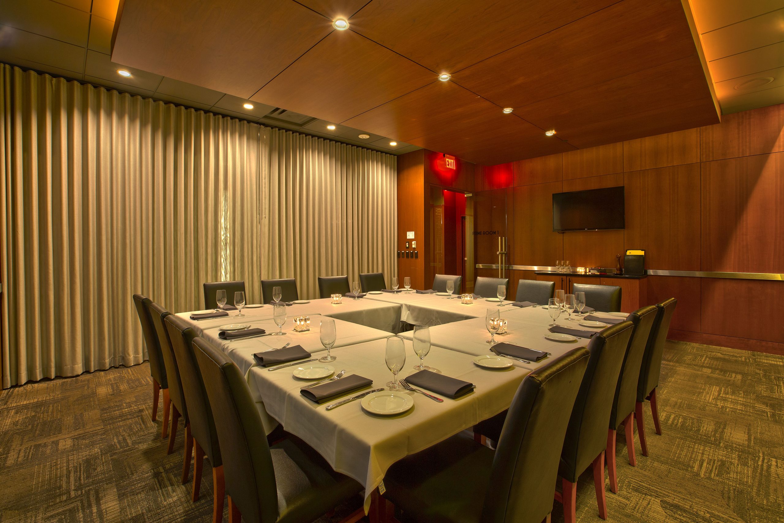 Prime Room 1 at Mitchell's Ocean Club with a square table setup, curtains and a TV