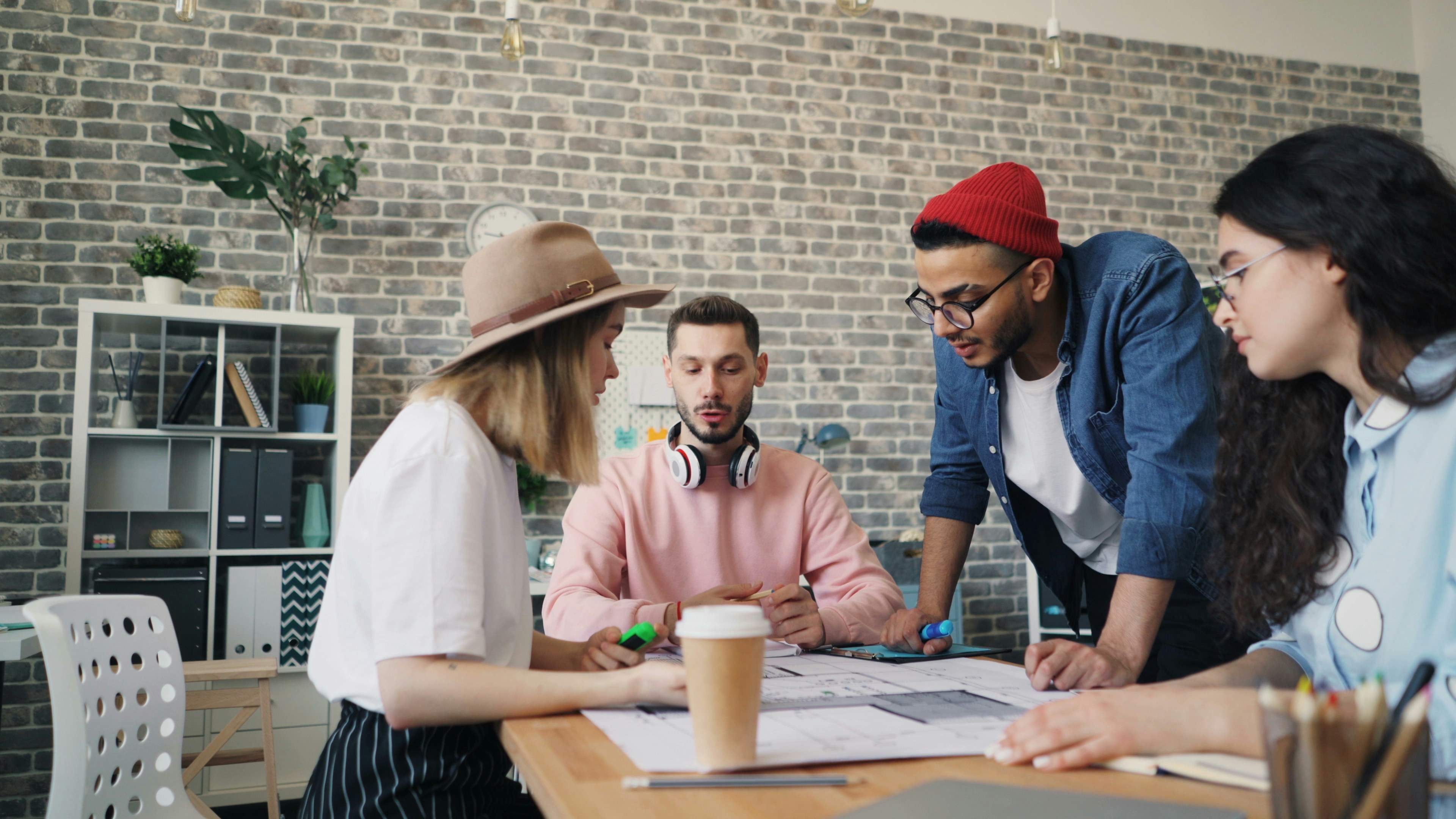 A diverse team collaborates around a table, analyzing documents and charts in a professional setting with a light green background.