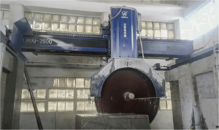 The Dinosaw LMDQ-2500 machine is actively cutting a granite block. Water is used to cool the cutting blade, and the machine is housed in a facility with glass block windows, highlighting its industrial application.