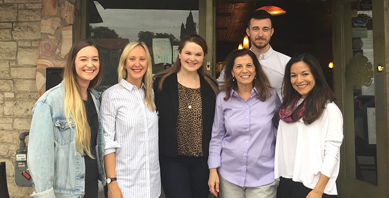 A photo of a group of people standing in front of a restaurant entrance.
