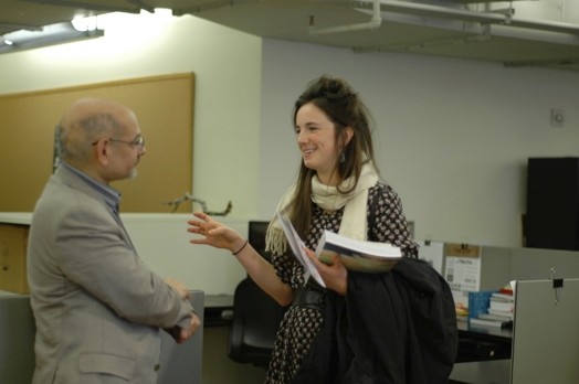 A photo of a man and a woman talking while holding a book.