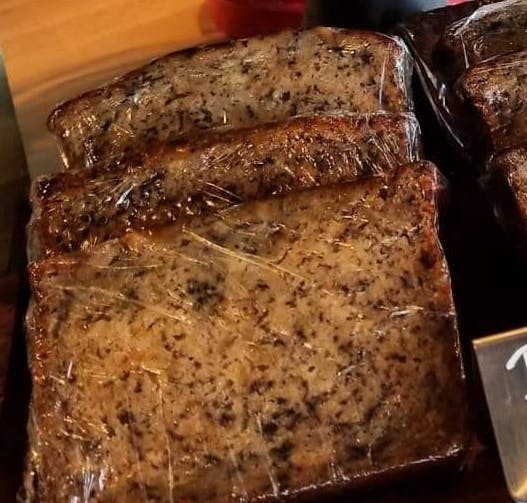 Thick, moist slices of homemade banana bread individually wrapped in clear film, showcasing a dark, rich crumb.
