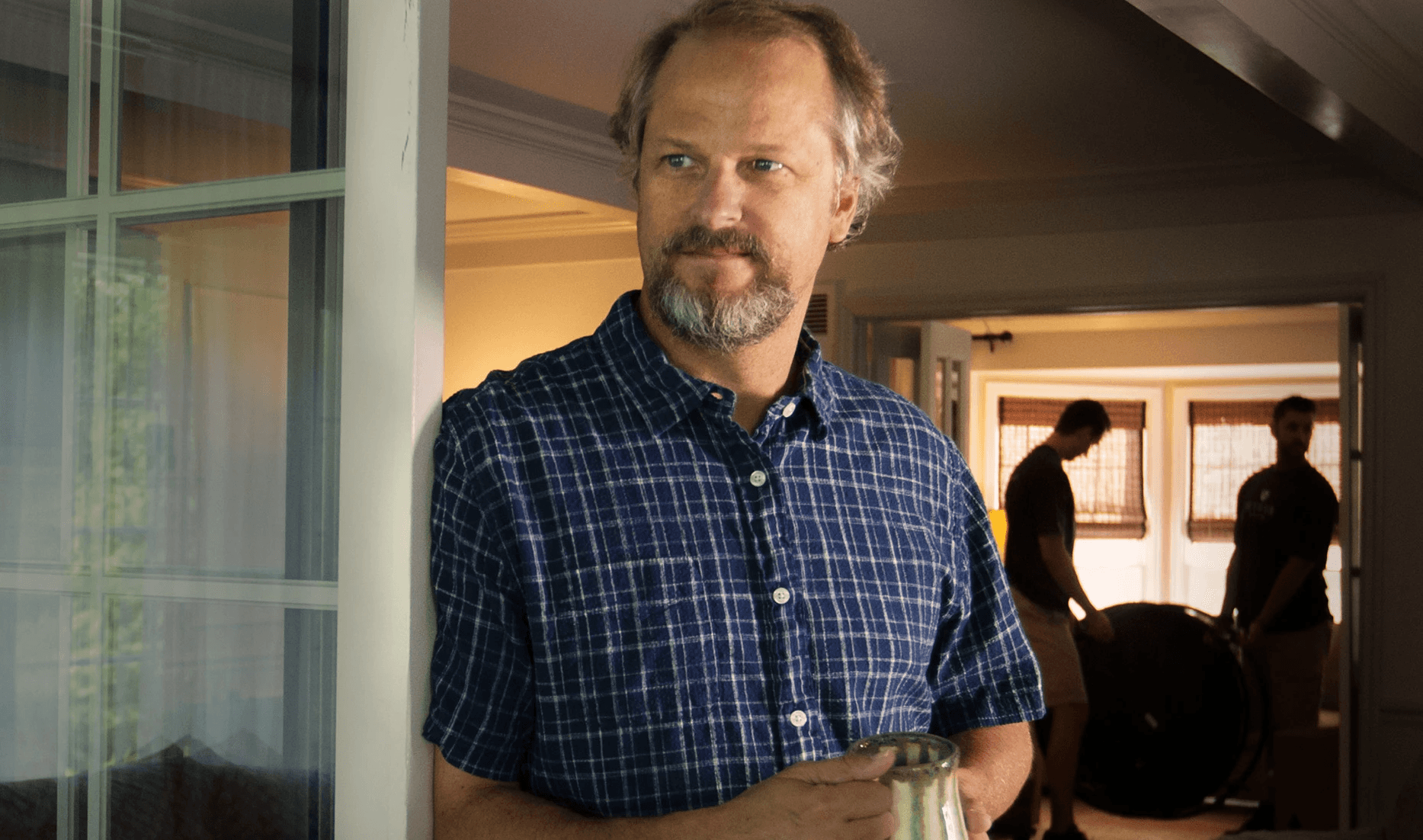 Man in plaid shirt, holding glass pitcher.