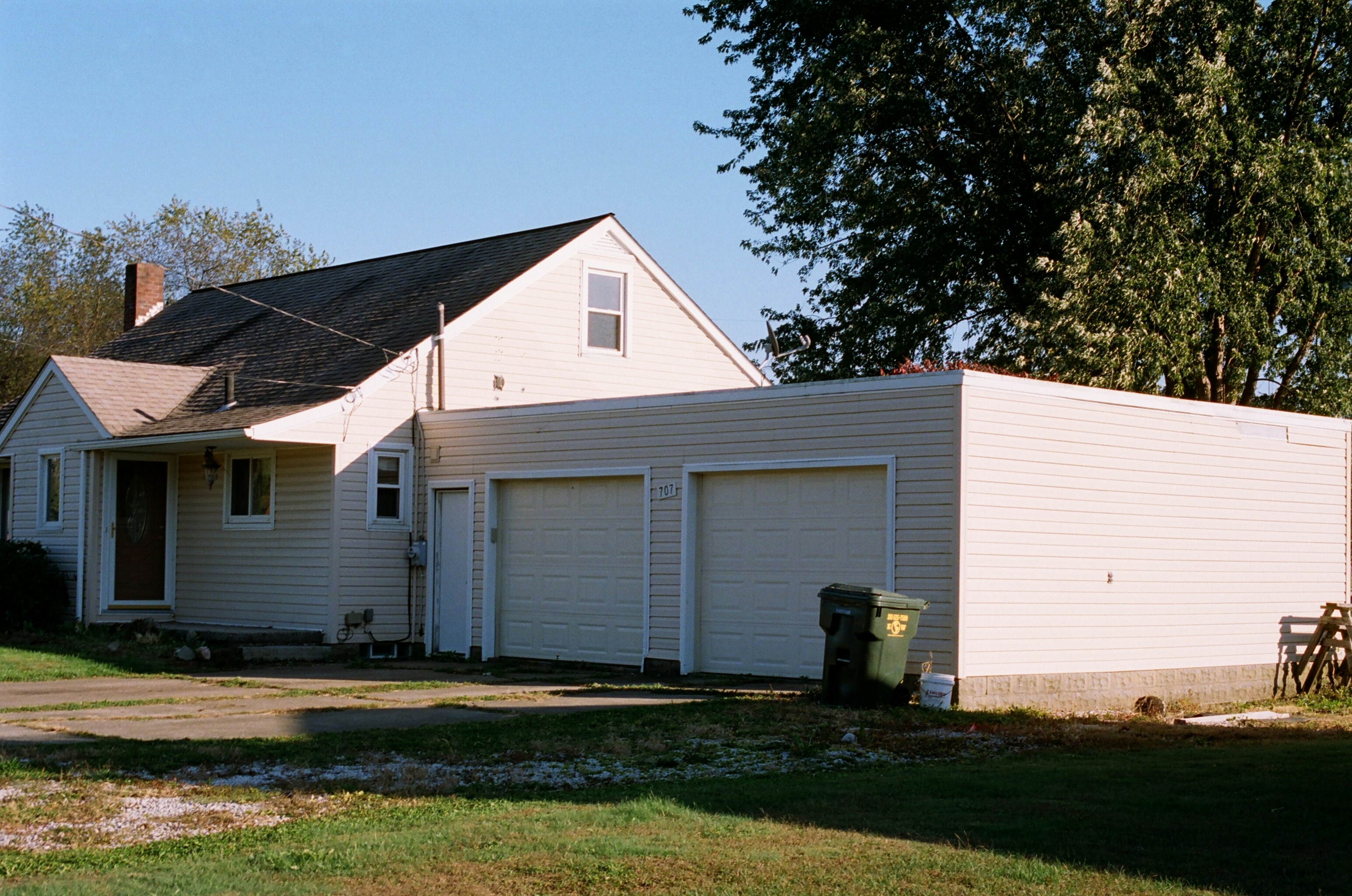 white and brown wooden house near green trees under blue sky during daytime