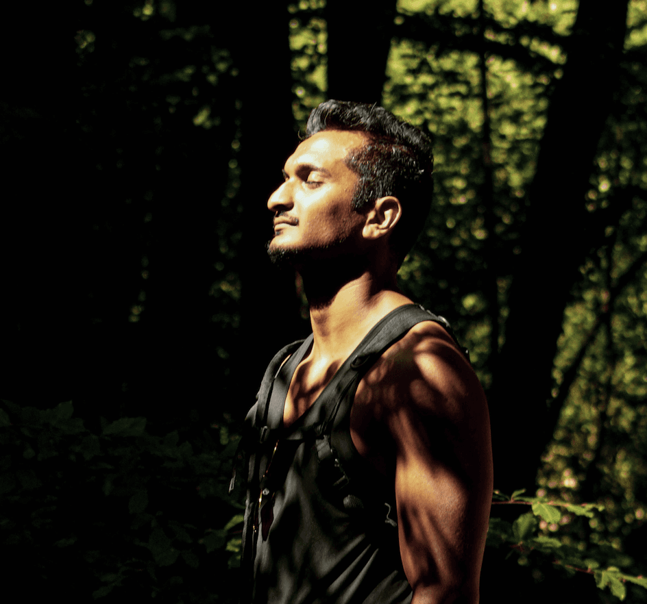 A muscular man standing in a forest with his eyes closed, symbolizing mindful motion and recovery from chronic pelvic pain in Oak Park, IL.