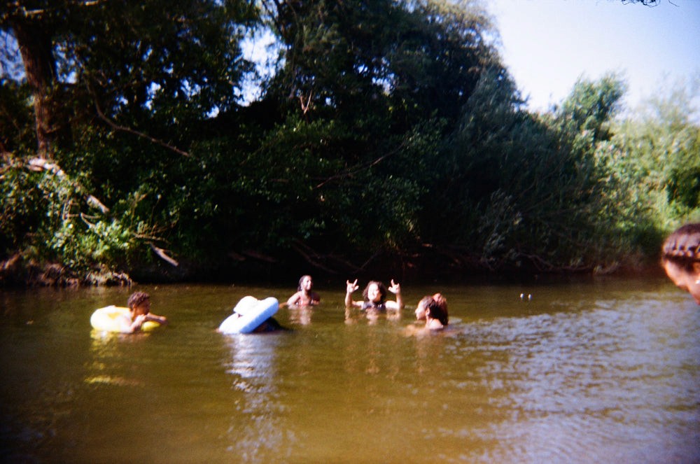 A group of people are swimming and playing around in a river