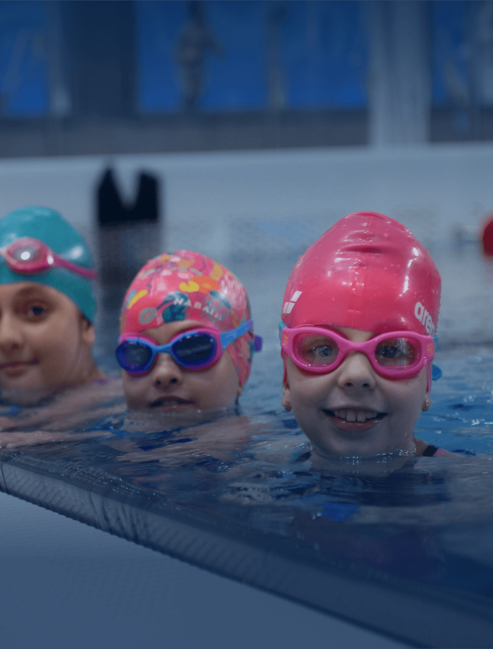 Kids wearing swimsuits standing in a pool with goggles.