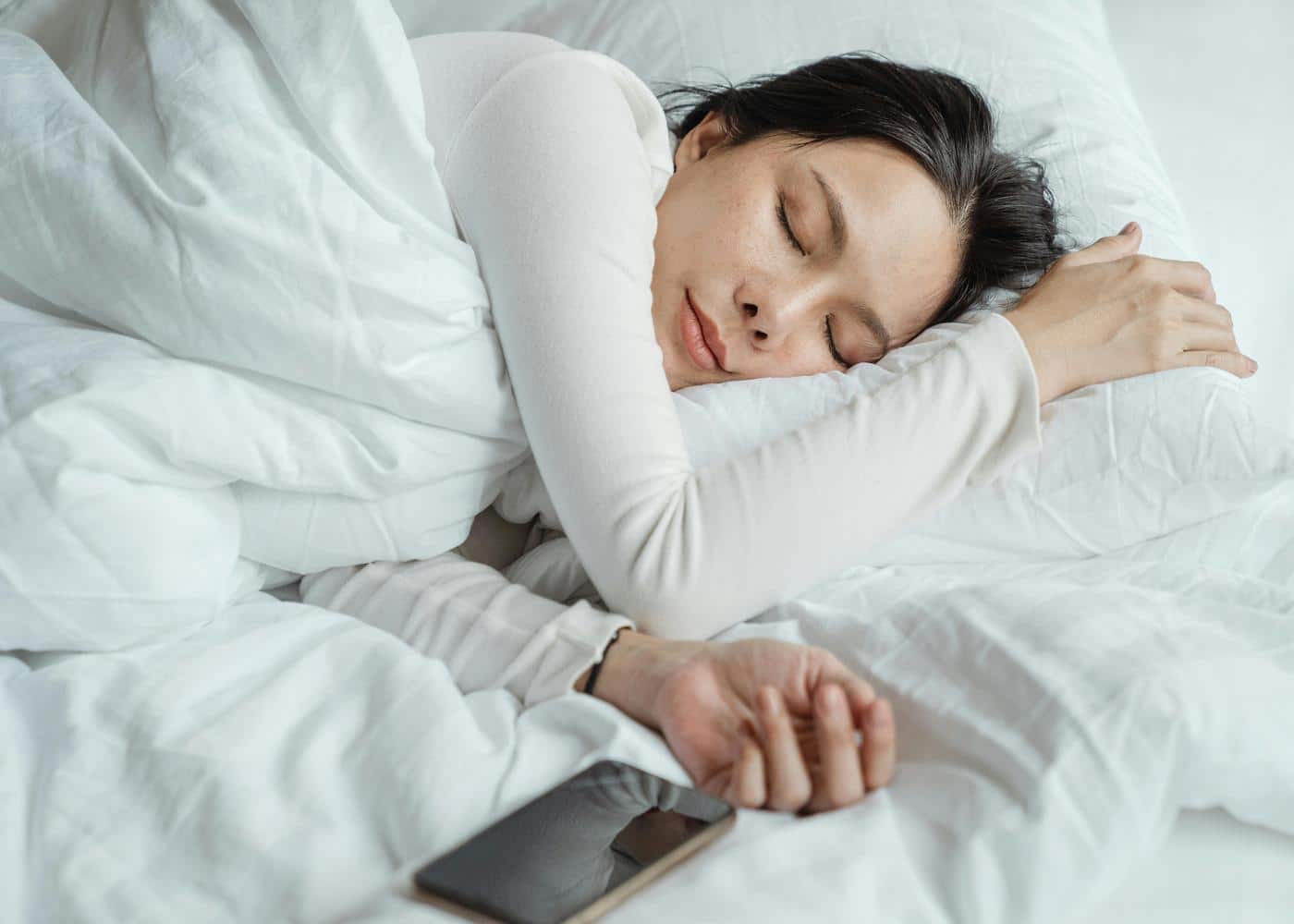 Free sleep hygiene apps - Woman sleeping next to her phone
