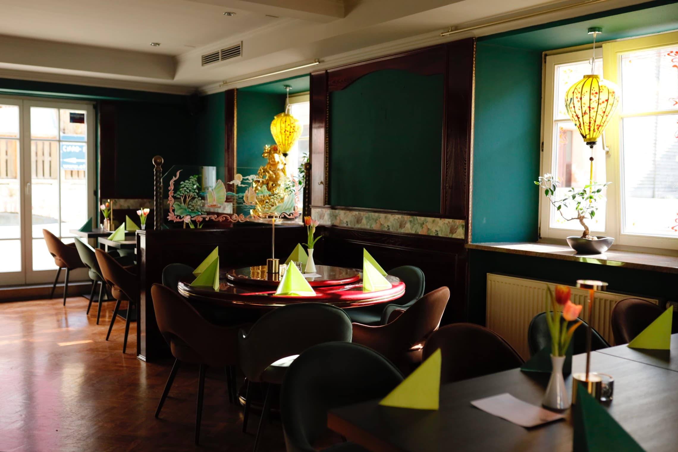Gemütliches Restaurant mit stilvoller Einrichtung. Runde Tische, grüne Wände und Dekorationen.